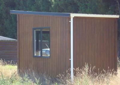 Stained timber OutaSpace cabin with a sliding window, sited on a rural property
