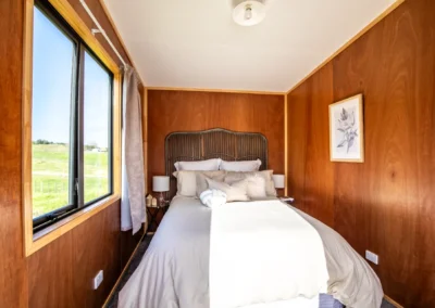 Cabin bedroom with a made-up double bed, bedside lamp and window