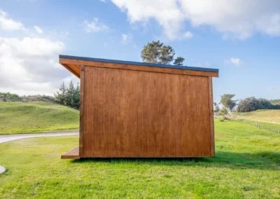Side view of an OutaSpace cabin showing the solid cedar weatherboard wall and low-pitch roofline