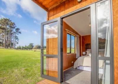 Open glass door of an OutaSpace cabin looking through to the bed inside