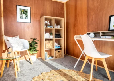 Cabin interior set up as a lounge, with plywood-lined walls, shelving unit and armchair